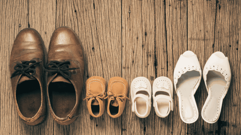 Braune Männerschuhe neben Kinderschuhen und Frauenschuhen als Symbol für klare Vaterrolle und familiäre Verantwortung