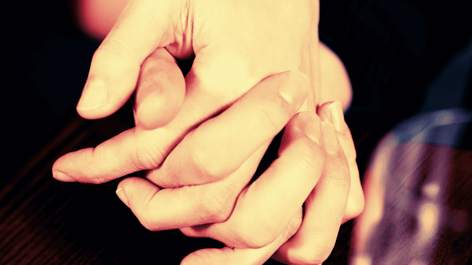 Zwei Hände halten sich ruhig am Tisch. Innere Haltung in der Familie zeigt sich in einer schlichten, zugewandten Berührung.